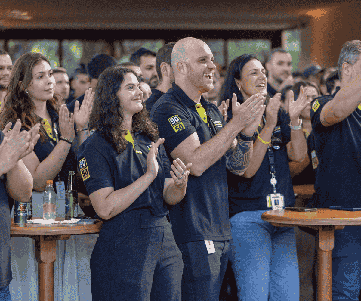 Colaboradores motivados aplaudindo durante evento interno, indicando sucesso da estratégia de endomarketing.